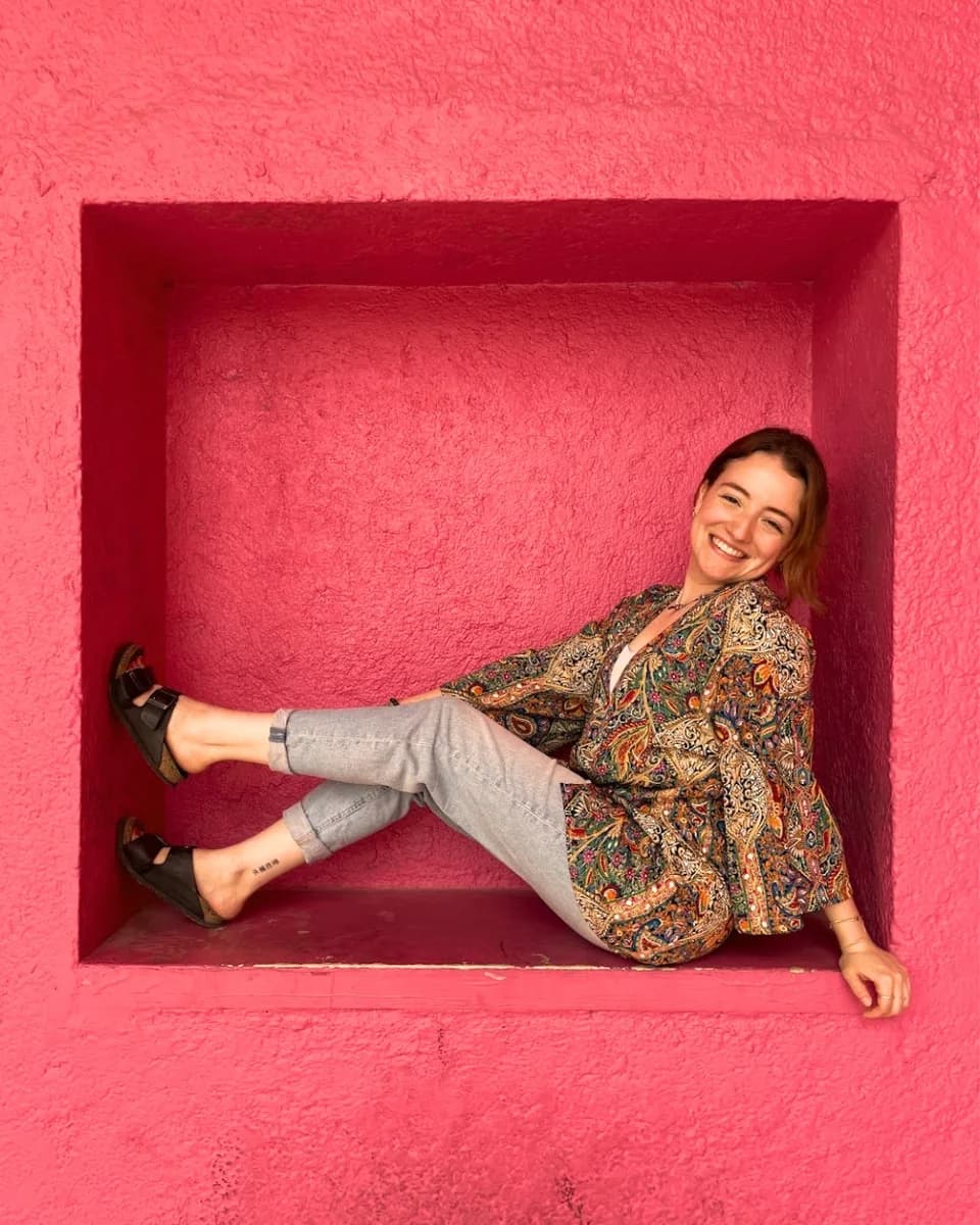 Retrato de Nancy sentada en un nicho de muro rosa